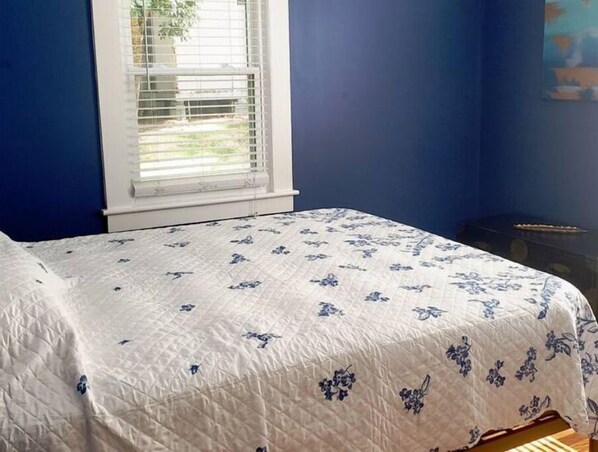 A bedroom with a bed, a window with blinds, and a blue wall. - Sunny Virginia Equestrian Cottage (Aiken)