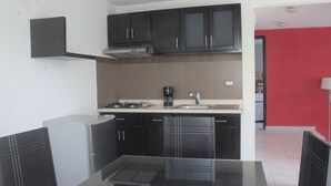 A modern kitchen with dark cabinets, a gas stove, and a coffee maker.