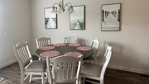 A dining area with a round table, six chairs, and three wall-mounted pictures. - Beautiful Townhouse ! (South Jordan)