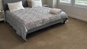 A bedroom with a bed, two nightstands, a window with blinds, and a carpeted floor. - Beautiful Townhouse ! (South Jordan)