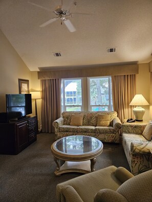 Relax in this stylish living room with a flat-screen TV, comfortable sofa, and armchairs.