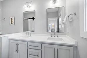 A modern bathroom with two sinks, a large mirror, and a towel rack.