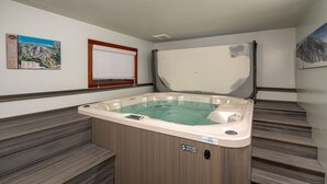 Ein Whirlpool in einem Raum mit Holzboden, einem Fenster mit Jalousien und einem Bild an der Wand.