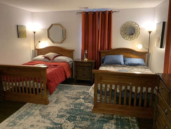 Ein Schlafzimmer mit zwei hölzernen Betten, einem Nachttisch, einer Kommode, einem Spiegel und einem Teppich.