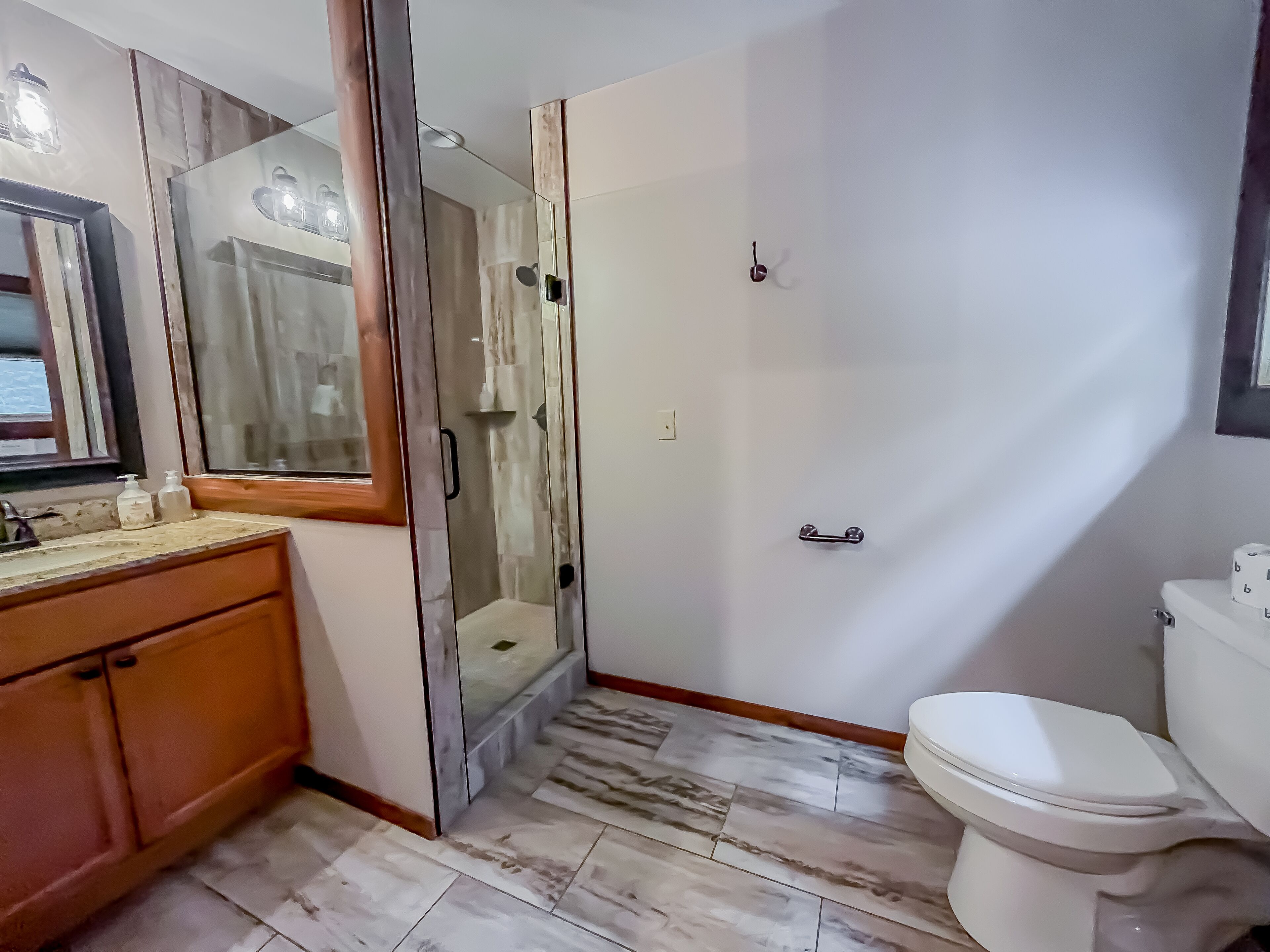 A bathroom with a glass-enclosed shower, a toilet, and a vanity with a mirror.