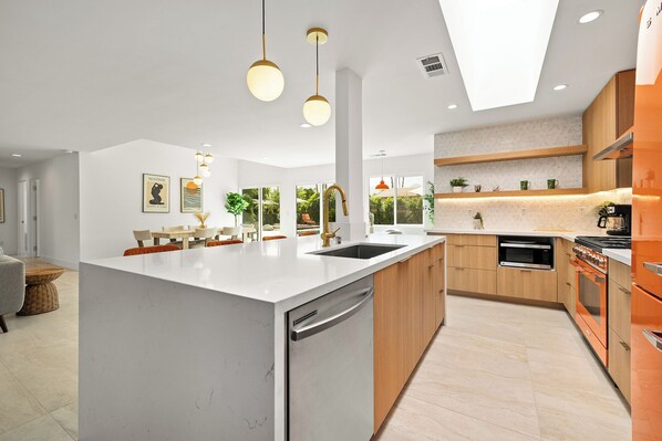 A modern kitchen with a central island, wooden cabinets, and a built-in oven.