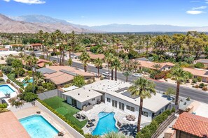 A residential area with multiple houses, a swimming pool, and a mountain backdrop.