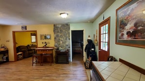 A spacious living room with a fireplace, a dining area with wooden furniture, and a kitchen area with a tiled backsplash. - Cabin, country setting, yet only minutes from everything! (Statesville)