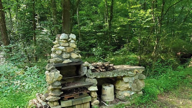 A stone-built outdoor grill in a forested area. - Cabin, country setting, yet only minutes from everything! (Statesville)