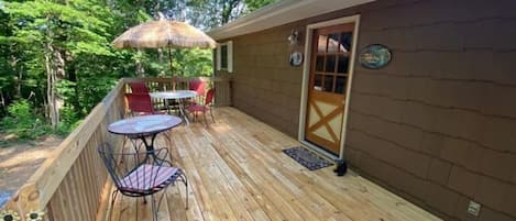 A wooden deck with a table and chairs, a door, and a small rug.