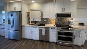A modern kitchen with white cabinets, stainless steel appliances, and a tiled backsplash.