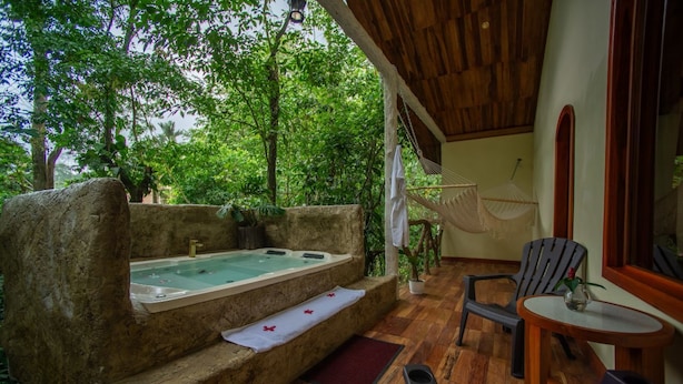 Ein Wellnessbereich mit Whirlpool, Holzterrasse und Sitzgelegenheiten.