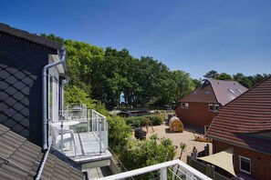 A residential area with a house featuring a glass balcony, a brick building, and a garden with a swing set. - Appartementanlage Eldena Wohnung Nr. 10 - Appartements Eldena (Middelhagen)