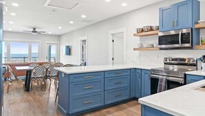 Une cuisine moderne avec des meubles bleus, un four en acier inoxydable et un coin repas offrant une vue agréable.