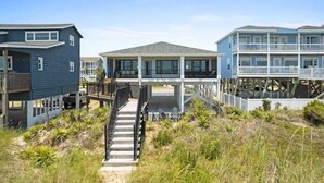 A beachfront property with a covered walkway, multiple levels, and a view of the ocean. - Cake by the Ocean by Brunswick Vacation Rentals: Fully Renovated Oceanfront Home (Holden Beach)