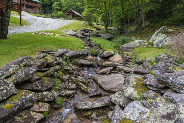 A rustic cabin with a wooden deck and a stone pathway leading to it.