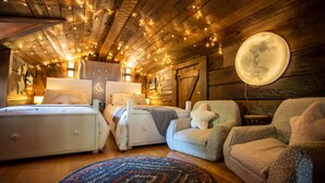 A cozy bedroom with two beds, a round rug, and a large moon decoration on the wall. - Creekside Cabin on Private Acreage (Banner Elk)
