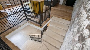 Un escalier avec une rampe en métal, un plancher en bois et un mur en pierre.