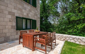 Relax on the patio surrounded by lush greenery and enjoy meals at the wooden table with comfortable seating for six.