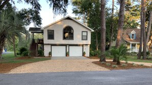 Una casa a due piani con un garage, circondata da alberi e un prato curato.