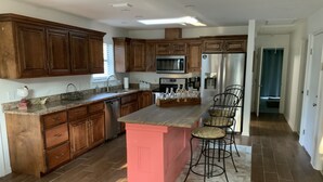 Una cucina moderna con mobili in legno, un'isola rosa e un frigorifero in acciaio inossidabile.