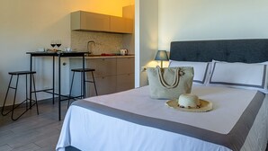 A hotel room with a bed, a nightstand, a lamp, a suitcase, and a dining area with a table and chairs. - Rosal 3-Giardini Naxos holiday home (Giardini Naxos)