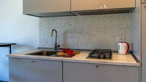 A modern kitchen with a stainless steel sink, a gas stove, and a kettle on the countertop. - Rosal 3-Giardini Naxos holiday home (Giardini Naxos)