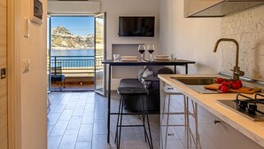 A modern kitchen with a view of the sea, a dining area with a table and chairs, and a balcony with a chair. - Rosal 3-Giardini Naxos holiday home (Giardini Naxos)