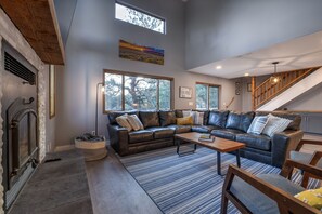 A spacious living area with a fireplace, leather sofas, a coffee table, and a staircase. - Circle J Ranch - 200+ acres of private Colorado experiences for family & friends (Lake George)