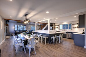 A modern kitchen with a central island, bar stools, and a dining area with a long table and chairs. - Circle J Ranch - 200+ acres of private Colorado experiences for family & friends (Lake George)