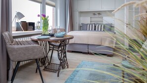 Ein Schlafzimmer mit Bett, Nachttisch, Sessel und Fenster mit Blick ins Freie.