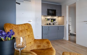 Un salon moderne avec un canapé, un verre de vin et un vase de fleurs.