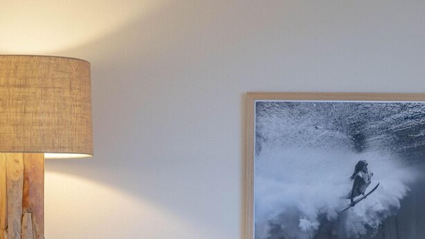 A modern living room with a sofa, a lamp, a framed picture, and a small table with glasses. - 1-zimmerwohnung in Direkter Nähe zum Weitläufigen, Feinsandigen Strand - Andreas-dirks-straße 1 (Sylt)