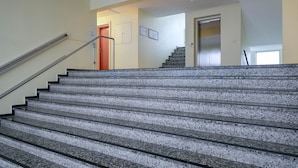 A staircase with granite steps and a metal handrail, leading to a door with a red frame. - 1-zimmerwohnung in Direkter Nähe zum Weitläufigen, Feinsandigen Strand - Andreas-dirks-straße 1 (Sylt)