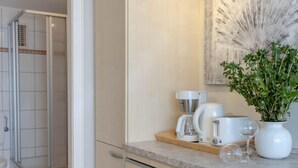 A modern kitchen with a countertop, a coffee maker, a toaster, and a potted plant. - 1-zimmerwohnung in Direkter Nähe zum Weitläufigen, Feinsandigen Strand - Andreas-dirks-straße 1 (Sylt)
