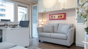 Ein modernes Wohnzimmer mit einer Couch, einem kleinen Tisch und einem Fenster.