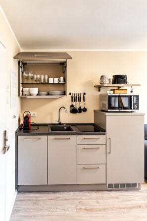 Una cocina moderna con microondas incorporado, un lavamanos y una encimera con hervidor.