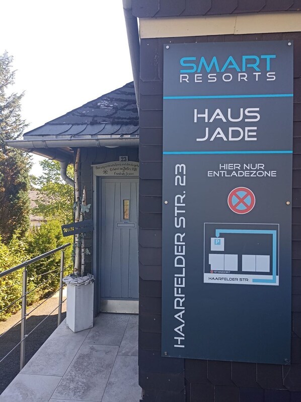 A sign for Smart Resorts Haus Jade, indicating a parking area with a no parking zone and a stand.