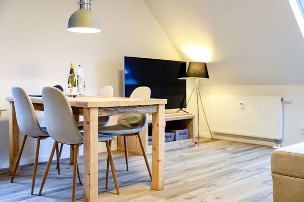 Un coin repas avec une table et des chaises en bois, un téléviseur et un lampadaire.