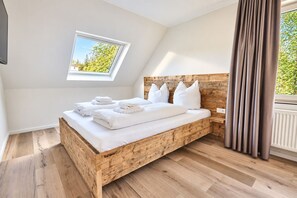 A bedroom with a sloped ceiling, a skylight, a wooden headboard, a bed with white linens, and a window with curtains. - Smart Resorts - Haus Opal - Ferienwohnung 404 mit 1 Schlafzimmer, Max. 4 Personen - Smart Resorts (Winterberg)