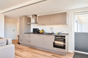 Una cocina moderna con horno integrado, cafetera y frutero sobre la encimera.