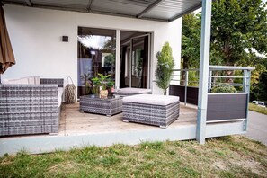 A modern outdoor patio with wicker furniture, a glass door entrance, and a small garden area. - Smart Resorts - Haus Opal - Ferienwohnung 401 mit 3 Schlafzimmern, Max. 8 Personen - Smart Resorts (Winterberg)