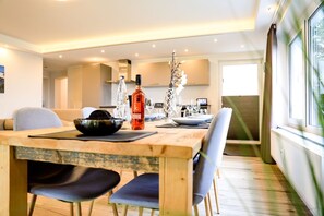 A modern dining area with a wooden table, black chairs, and a bottle of wine. - Smart Resorts - Haus Opal - Ferienwohnung 401 mit 3 Schlafzimmern, Max. 8 Personen - Smart Resorts (Winterberg)