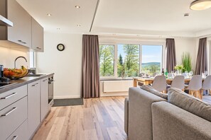 A modern kitchen with a dining area, large windows, and a view of the outdoors.