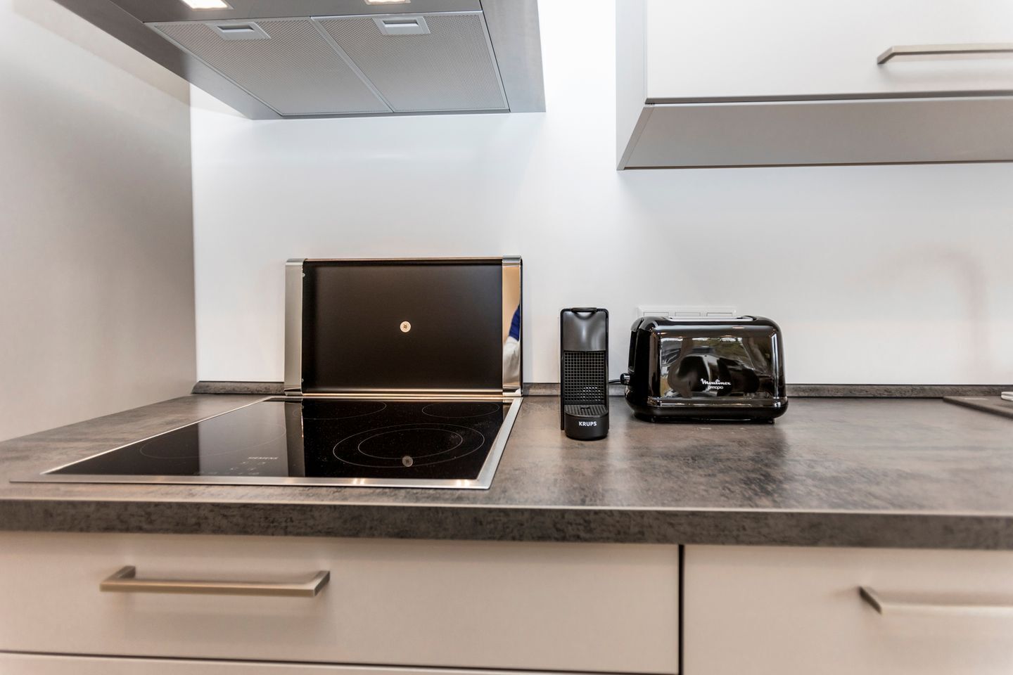 A modern kitchen with a built-in induction cooktop, a coffee maker, and a toaster on the countertop.