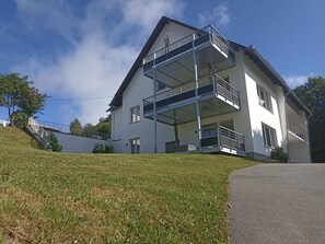 Kaksikerroksinen talo, jossa on parveke ja pieni puutarha.