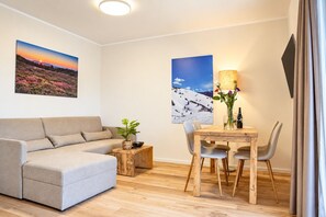 A modern living room with a sofa, a dining table with chairs, and two wall-mounted paintings. - Smart Resorts - Opal House - Apartment 402 with 1 bedroom and a balcony, (Winterberg)