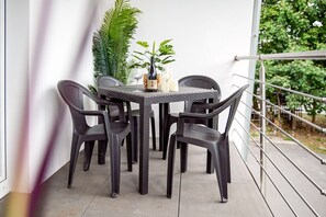 Ein Balkon mit Tisch und Stühlen, umgeben von Blumentöpfen und einem Geländer.