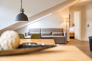 A modern loft-style living space with a sofa, dining table, and pendant lighting.