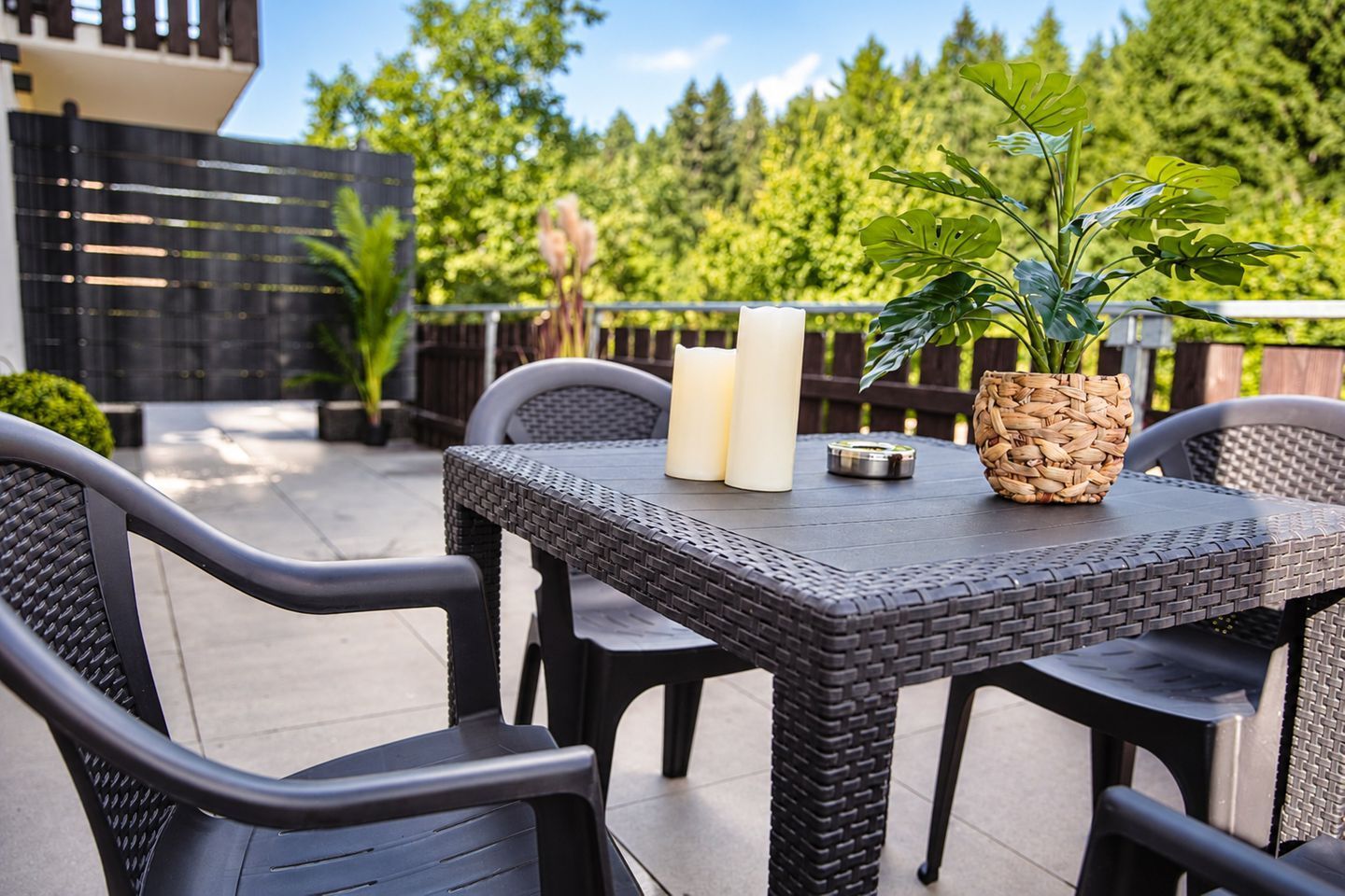 An outdoor patio with a table, chairs, and a potted plant.